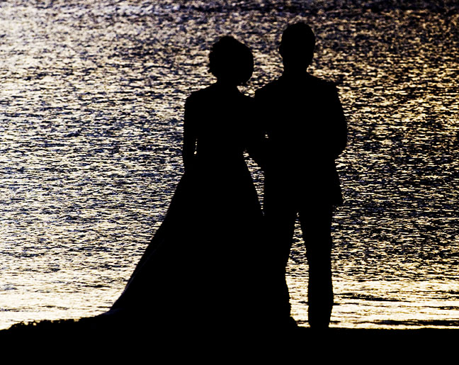 Destination weddings. Newlyweds watch the sunset on the beach. Photo by Alina Oswald.