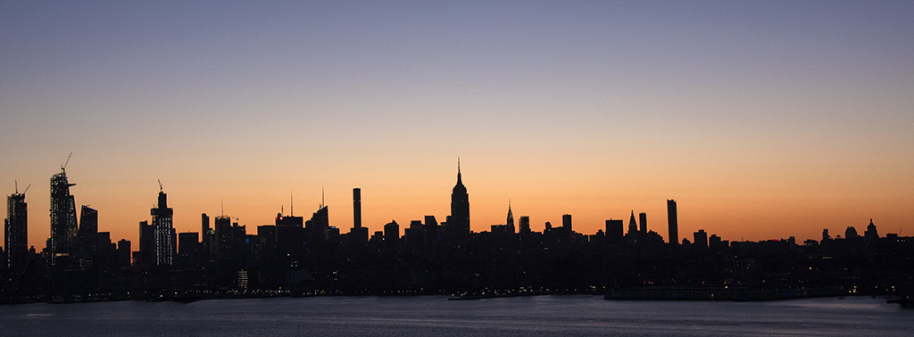Pano view of NYC silhouetted by sunrise light. Photo by Alina Oswald. All Rights Reserved.