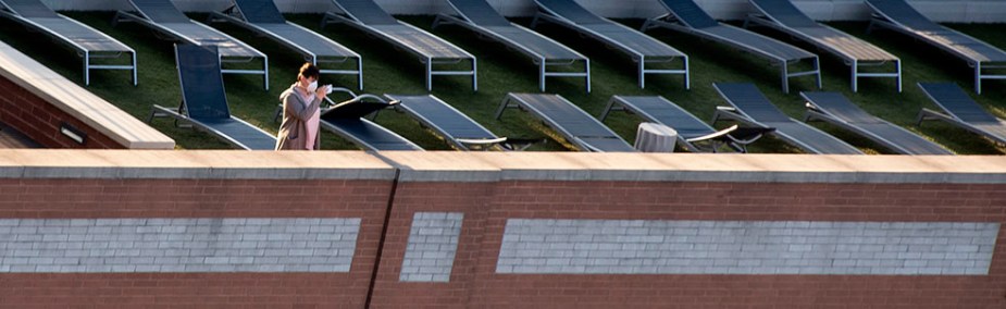 Covid-19 Life: On an empty deck, a lonely individual wearing face mask snaps pictures of the street below. ©Alina Oswald.