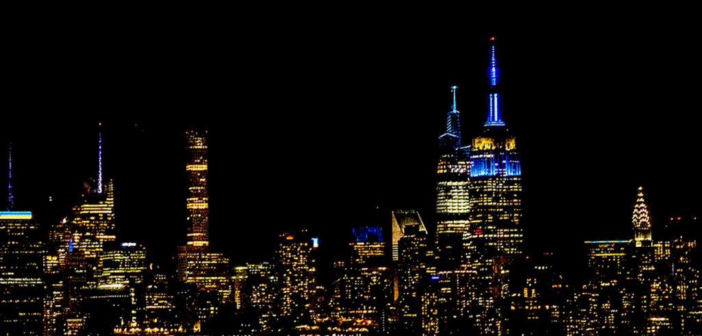 NYC skyline at night, illuminated in blue and yellow lights, in solidarity with Ukraine. ©Alina Oswald.