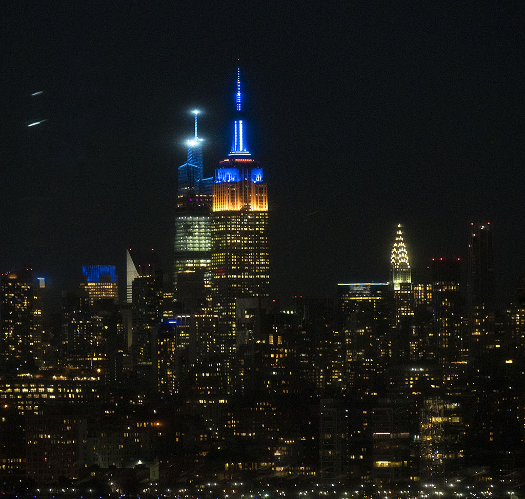 NYC skyline at night, illuminated in blue and yellow lights, in solidarity with Ukraine. ©Alina Oswald.